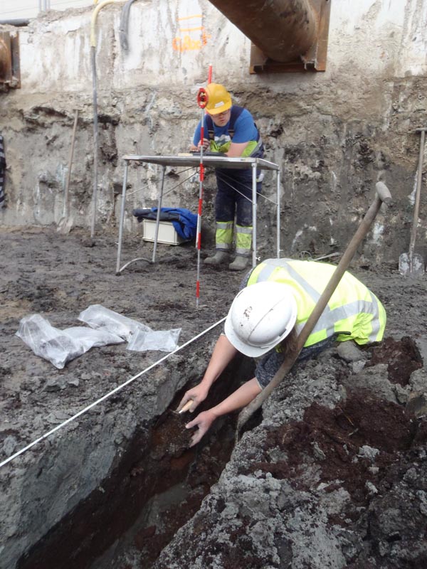 Archeoloog bestudeert en spoor en meet het in.