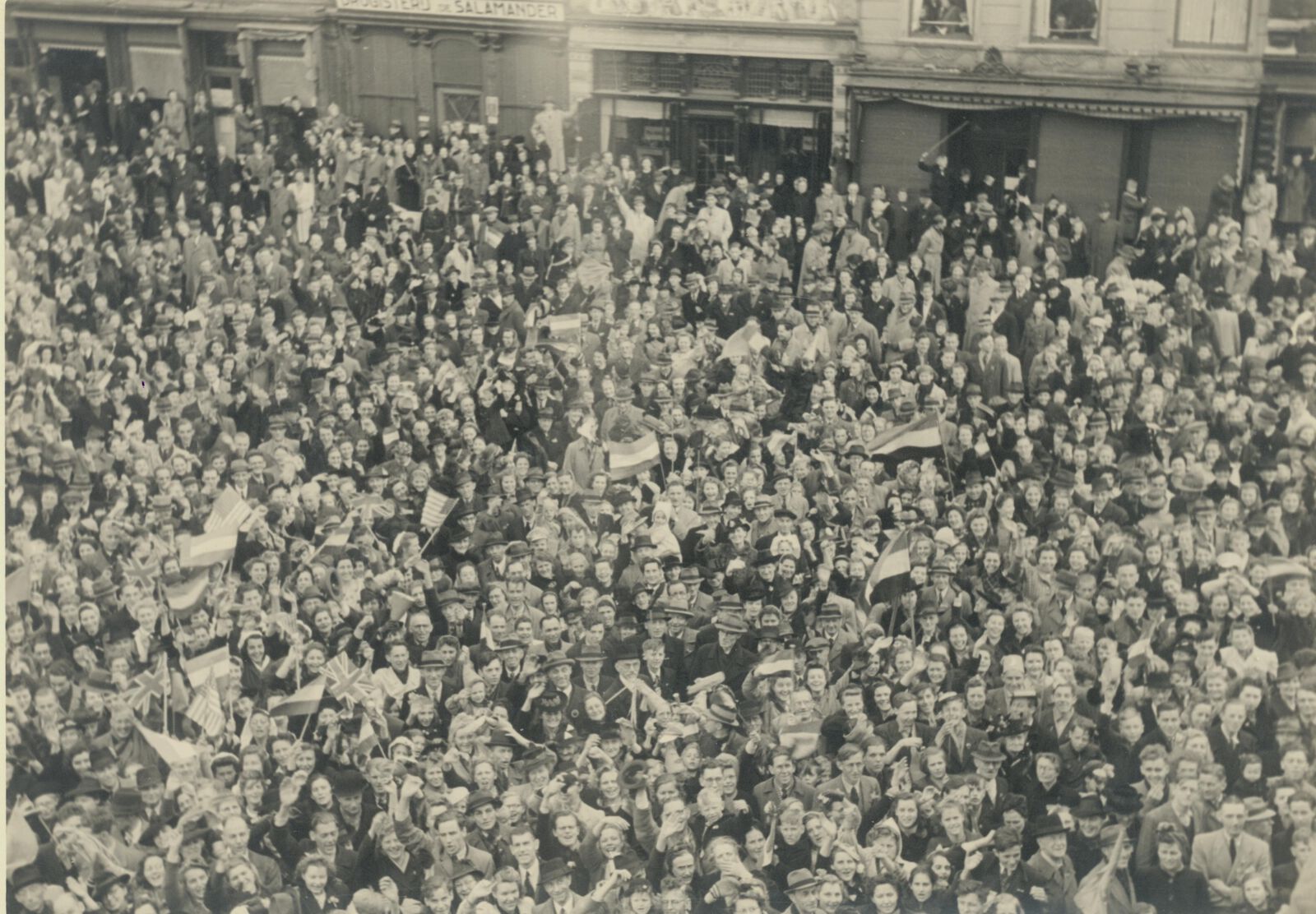 Mensen met vlaggen vieren de bevrijding in 1945 op de Markt in Delft.
