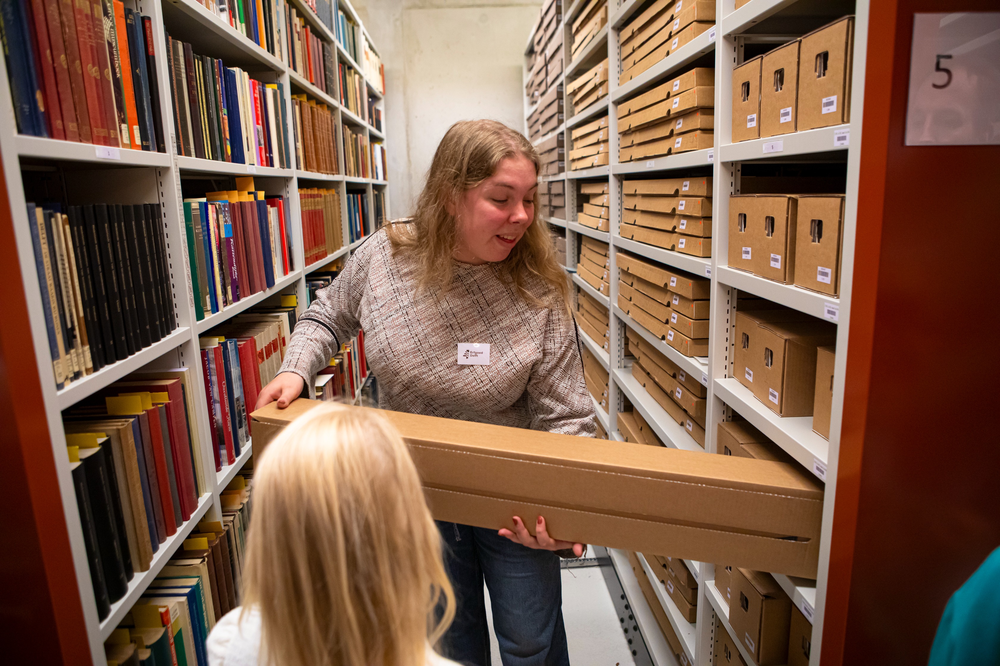 Een vrouw haalt een archiefstuk uit het depot.